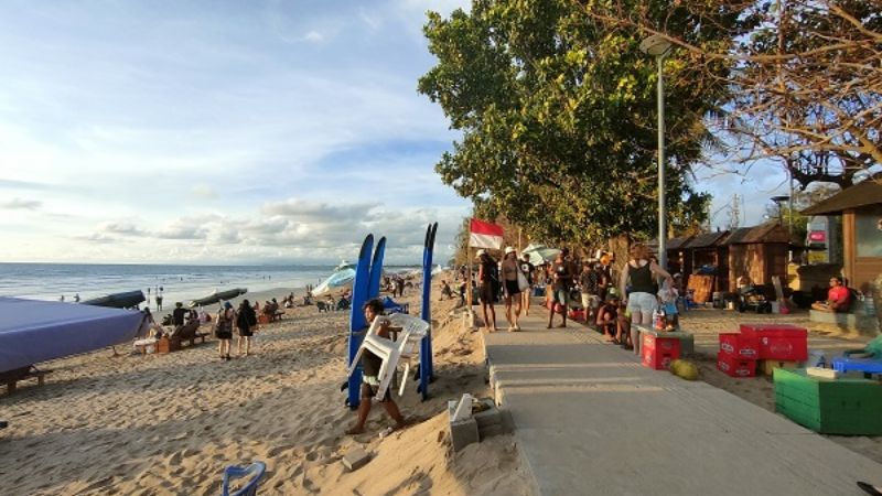 2026年のクタビーチの砂浜とサーフィンを楽しむ旅行者の風景